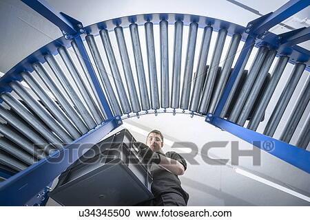 Low angle view of apprentice with crates on production line View Large Photo Image Stock Image - Low angle view of apprentice with crates on production line. Fotosearch