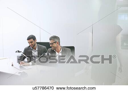 Stock Image - Male business colleagues using digital tablet in office. Fotosearch