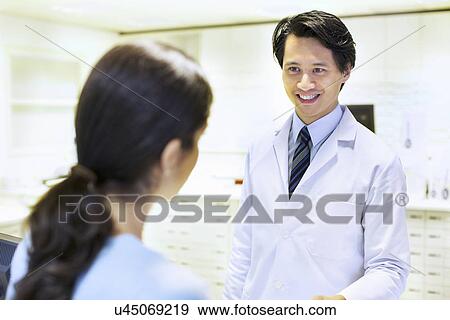 Male pharmacist handing prescription to customer View Large Photo Image Stock Photo - Male pharmacist handing prescription to customer. Fotosearch