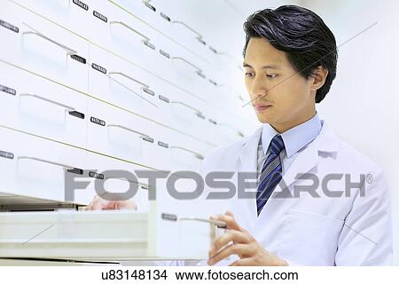 Picture - Male pharmacist searching for medications in pharmacy. Fotosearch