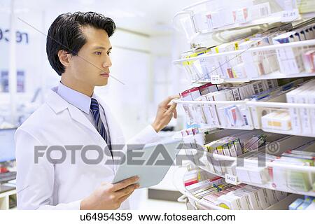 Male pharmacist stock taking in pharmacy View Large Photo Image Stock Photo - Male pharmacist stock taking in pharmacy. Fotosearch