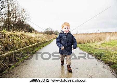 Male toddler running along rural road View Large Photo Image Stock Image - Male toddler running along rural road. Fotosearch