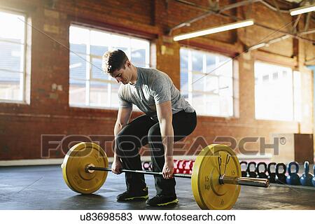 Stock Image - Man lifting weights in gymnasium. Fotosearch