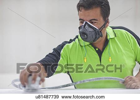 Stock Photo - Man sanding down wooden plank in carpenters workshop. Fotosearch