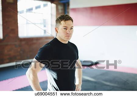 Man standing in gym with hands on hips View Large Photo Image Stock Image - Man standing in gym with hands on hips. Fotosearch