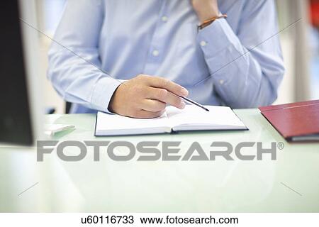 Stock Image - Mature businessman organizing his diary. Fotosearch