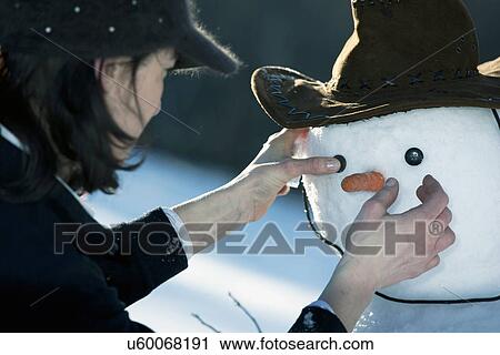 Mature woman placing the eyes on a snowman face View Large Photo Image Stock Image - Mature woman placing the eyes on a snowman face. Fotosearch