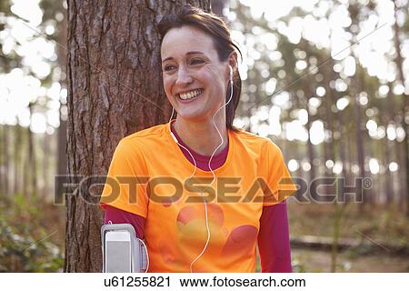 Mature woman runner with earphones taking a break in a forest View Large Photo Image Stock Image - Mature woman runner with earphones taking a break in a forest. Fotosearch