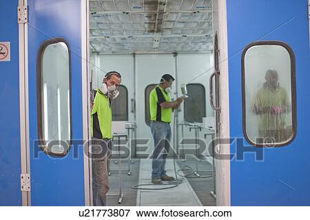 Stock Photo - Men working in spray painting workshop. Fotosearch