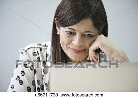 Mid adult businesswoman looking at laptop View Large Photo Image Stock Photo - Mid adult businesswoman looking at laptop. Fotosearch