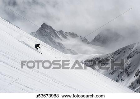 Stock Photo - Mid adult man skiing down steep hill, Obergurgl, Austria. Fotosearch