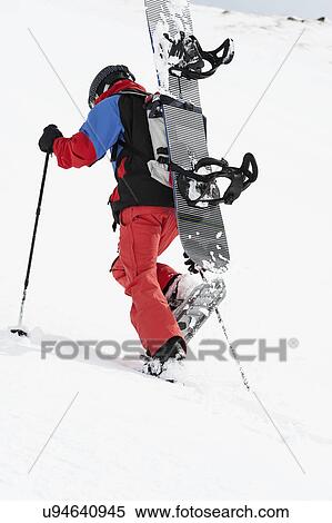 Stock Photography - Mid adult snowboarder walking uphill, Obergurgl, Austria. Fotosearch