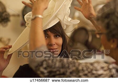 Mid adult woman trying on hat in milliners shop View Large Photo Image Stock Photo - Mid adult woman trying on hat in milliners shop. Fotosearch