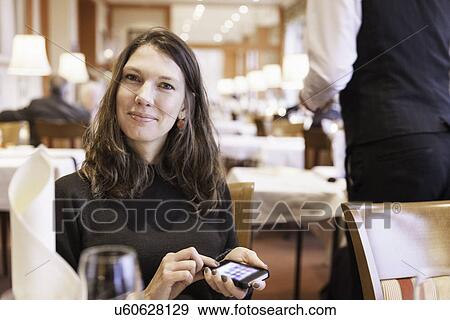 Mid adult woman with smartphone in restaurant View Large Photo Image Stock Photo - Mid adult woman with smartphone in restaurant. Fotosearch
