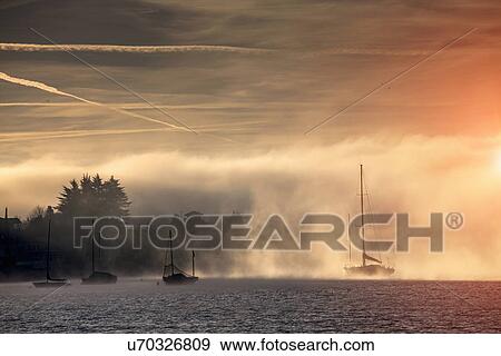 Stock Photo - Mist and yachts on Lake Maggiore, Piemonte, Novara, Italy. Fotosearch