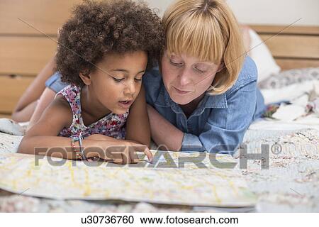 Mother and daughter lying on bed, looking at map View Large Photo Image Stock Image - Mother and daughter lying on bed, looking at map. Fotosearch