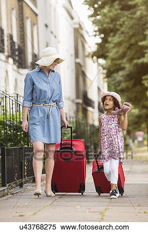 Mother and daughter pulling suitcases along pavement View Large Photo Image Stock Photography - Mother and daughter pulling suitcases along pavement. Fotosearch