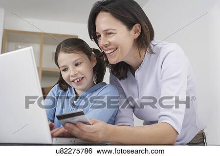 Mother and young daughter shopping online View Large Photo Image Stock Photograph - Mother and young daughter shopping online. Fotosearch