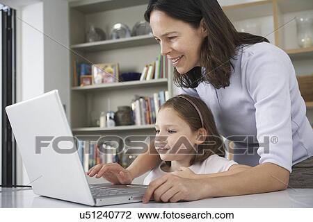 Stock Image - Mother and young daughter using laptop. Fotosearch
