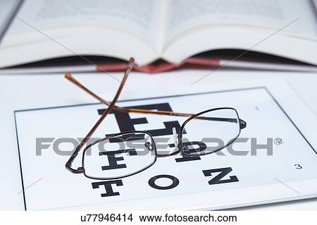 Picture - Pair of spectacles on Snellen eye chart. Fotosearch