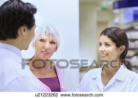 Stock Image - Pharmacists chatting to customer on medication. Fotosearch