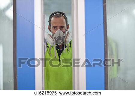 Stock Photography - Portrait of carpenter in spray painting workshop doorway. Fotosearch