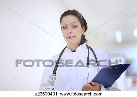 Stock Image - Portrait of female doctor holding clip board. Fotosearch
