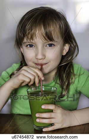 Stock Image - Portrait of girl drinking a glass of vegetable juice. Fotosearch