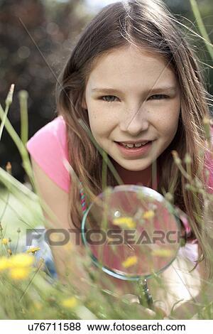 Portrait of girl lying in grass with magnifying glass View Large Photo Image Stock Photo - Portrait of girl lying in grass with magnifying glass. Fotosearch