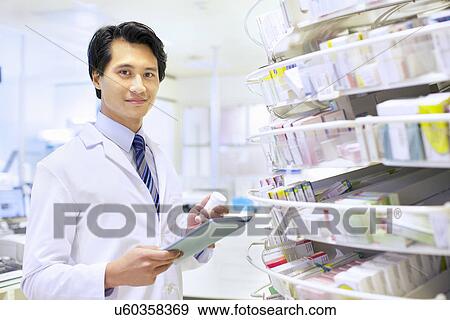 Stock Photo - Portrait of male pharmacist stock taking in pharmacy. Fotosearch