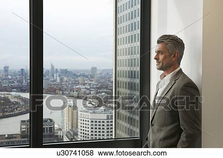 Portrait of mature businessman looking out of office window, Canary Wharf, London, UK View Large Photo Image Stock Photo - Portrait of mature businessman looking out of office window, Canary Wharf, London, UK. Fotosearch