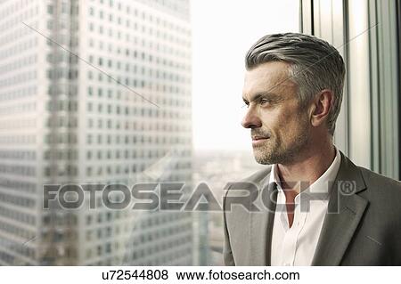 Portrait of mature businessman looking out of office window View Large Photo Image Stock Photo - Portrait of mature businessman looking out of office window. Fotosearch