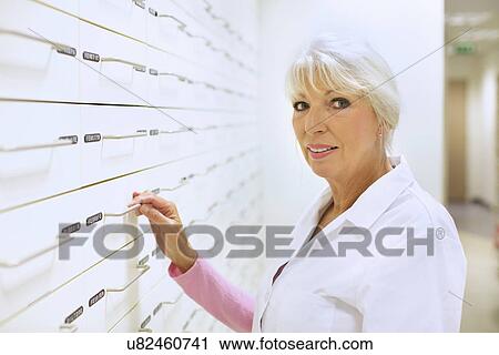 Stock Image - Portrait of mature female pharmacist at work. Fotosearch