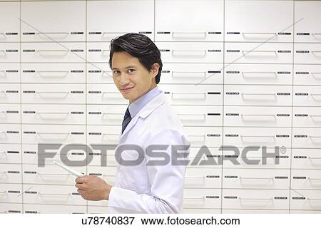 Stock Photo - Portrait of mid adult male pharmacist at work. Fotosearch