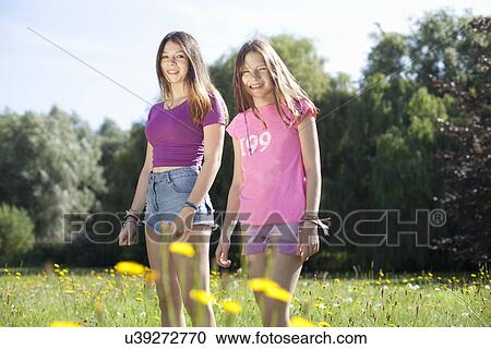 Stock Image - Portrait of teenage girl and her sister in park. Fotosearch