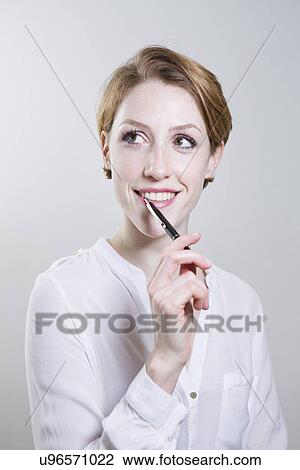 Stock Image - Portrait of young woman, holding pen. Fotosearch