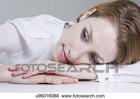 Stock Photo - Portrait of young woman, resting head on arm. Fotosearch