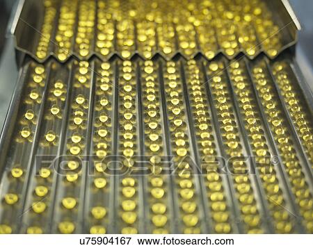 Stock Photo - Rows of vitamin capsules in pharmaceutical factory. Fotosearch