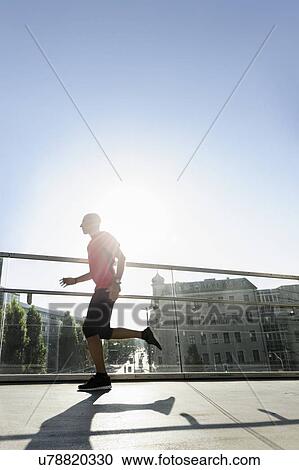 Stock Image - Runner crossing bridge, Munich, Germany. Fotosearch
