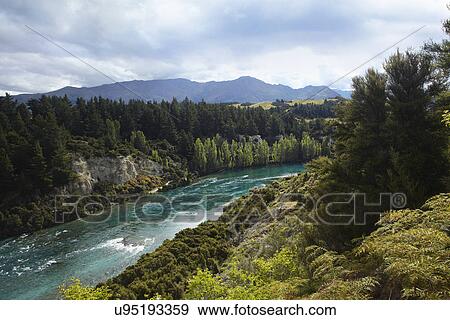 Stock Photo - Scenic view of river, forest and mountains, New Zealand. Fotosearch