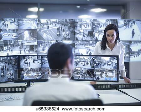 Picture - Security guards working at CCTV screens in control room. Fotosearch