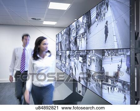 Security workers walking past CCTV screens in control room View Large Photo Image Stock Image - Security workers walking past CCTV screens in control room. Fotosearch