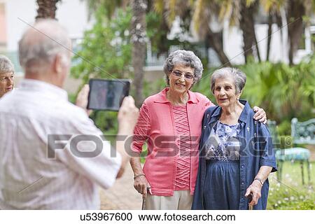 Senior man photographing friends in retirement villa garden View Large Photo Image Stock Image - Senior man photographing friends in retirement villa garden. Fotosearch