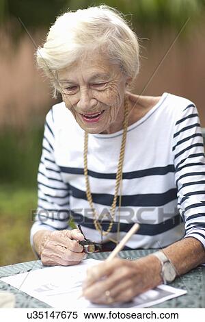 Stock Photography - Senior woman drawing in retirement villa garden. Fotosearch