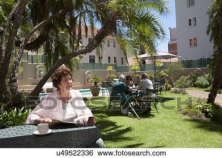 Senior woman having coffee in garden of retirement villa View Large Photo Image Stock Photograph - Senior woman having coffee in garden of retirement villa. Fotosearch