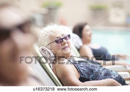 Stock Photo - Senior women on sun loungers in retirement villa garden. Fotosearch