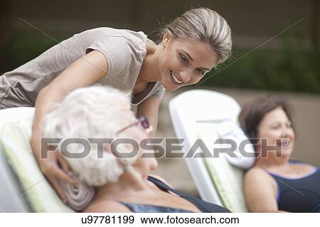 Stock Photo - Senior women relaxing on loungers in retirement villa garden. Fotosearch