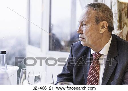Serious senior adult business man sitting alone in restaurant View Large Photo Image Stock Image - Serious senior adult business man sitting alone in restaurant. Fotosearch