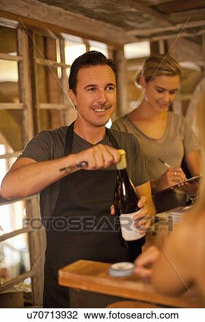 Sommelier opening bottle of wine in wine shop View Large Photo Image Stock Image - Sommelier opening bottle of wine in wine shop. Fotosearch