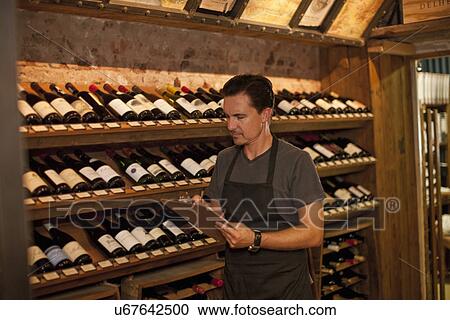 Stock Image - Sommelier stock taking in wine shop. Fotosearch